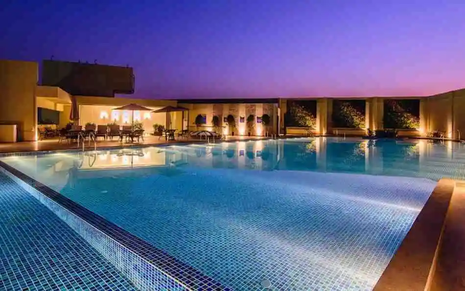 Swimming pool at dusk Swimming pool and deck lit at dusk in a Sattva Group community, artist's impression